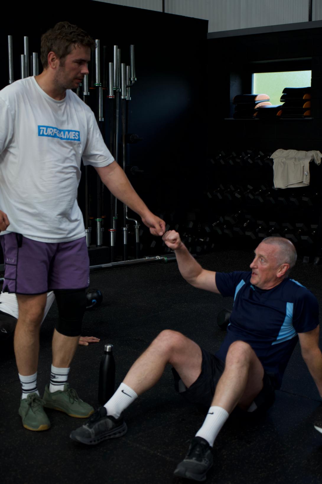 A coach sharing a laugh while helping an older member
